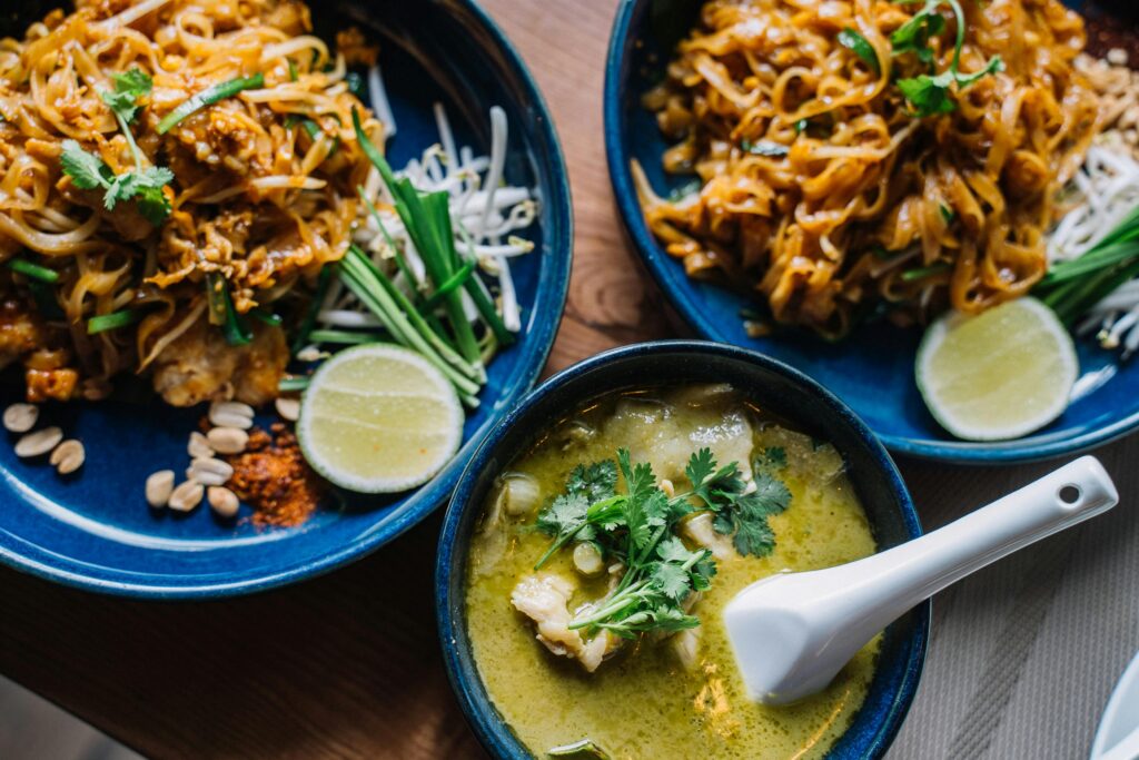 A plate of traditional Thai pad Thai, topped with fresh lime, peanuts, and green onions, showcasing a popular dish for ordering food in Thailand.